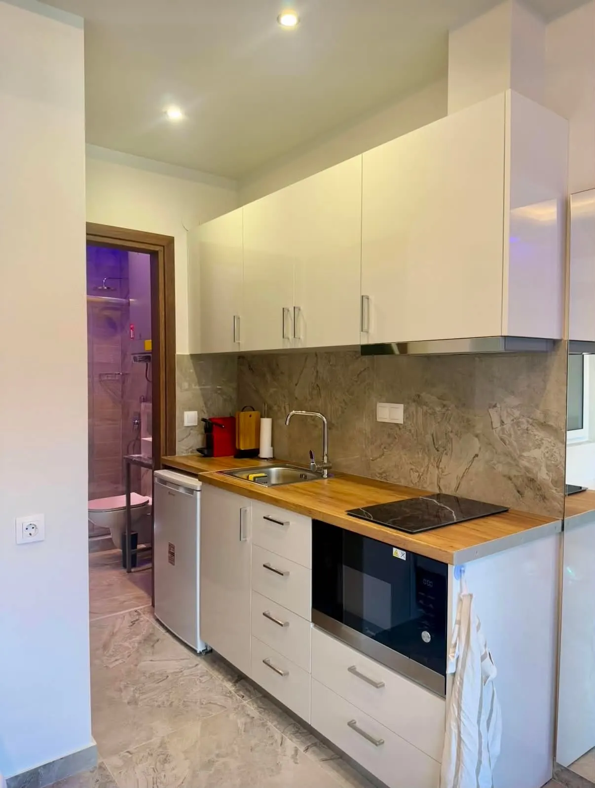 Az 53-as apartman konyhája fehér szekrényekkel, főzőlappal és mikrohullámú sütővel