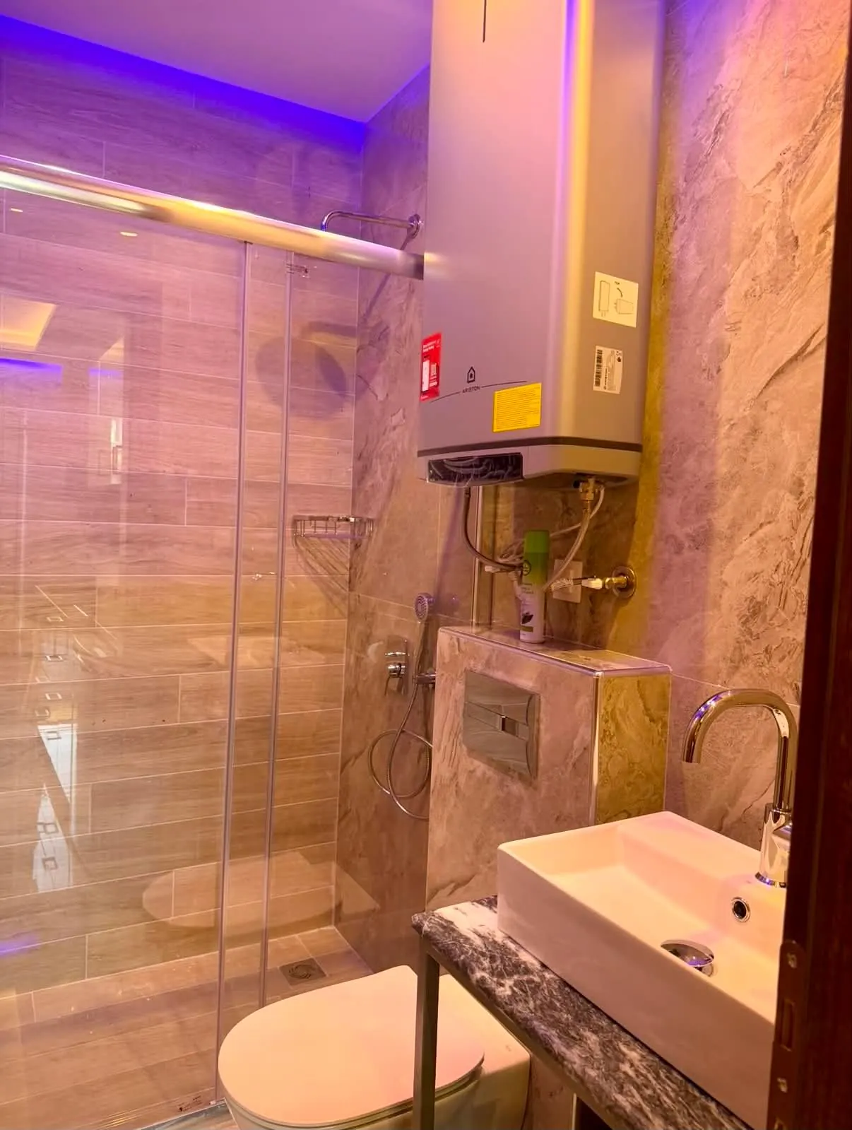 Az 53-as apartman fürdőszobája üvegfalú zuhanyzóval és kőhatású burkolattal